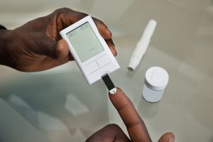 Close-up Of Patient Hands Measuring Glucose Level Blood Test With Glucometer